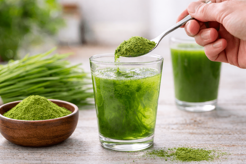 Weizengras Pulver wird in einem Glas Wasser angerührt und zu einem grünen Getränk gemischt